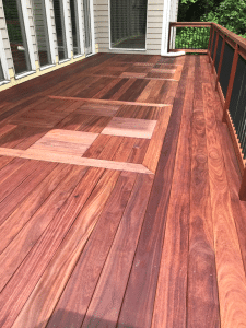 Cumaru hardwood deck with custom geometric pattern inlay, installed using face screw fasteners, showcasing rich natural grain and precision craftsmanship.