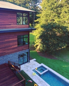Tigerwood rainscreen siding installed on a modern multi-story home exterior overlooking a backyard pool and landscaped lawn.
