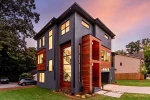 Modern three-story home featuring brown balau rainscreen siding accents against dark gray brick exterior at dusk