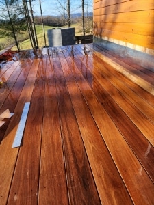 Champagne Cumaru hardwood deck boards glistening after rain with rich golden brown grain and smooth 1x6 decking installation