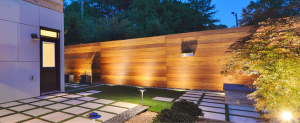 Modern ipe hardwood privacy fence with horizontal 1x6 boards, illuminated by landscape lighting in a contemporary backyard courtyard.