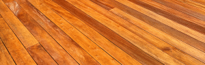 Close up of garapa hardwood decking boards highlighting natural golden color variation and tight straight grain pattern.