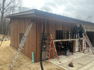 Brown Balau Rainscreen Siding Installation on Modern Garage Exterior Brown Balau rainscreen siding installation on modern residential garage with vertical hardwood cladding and construction crew on site