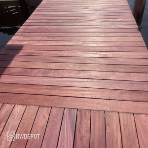 Weathered Purpleheart decking boards installed on an elevated backyard deck with visible grain variation and natural fading tones.
