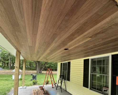 Brown Balau tongue and groove porch ceiling before maintenance oil, showing the natural weathered appearance of the hardwood.